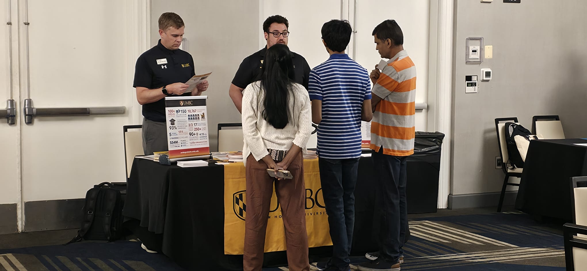 UMBC admissions team speaking with a family at the UMBC table