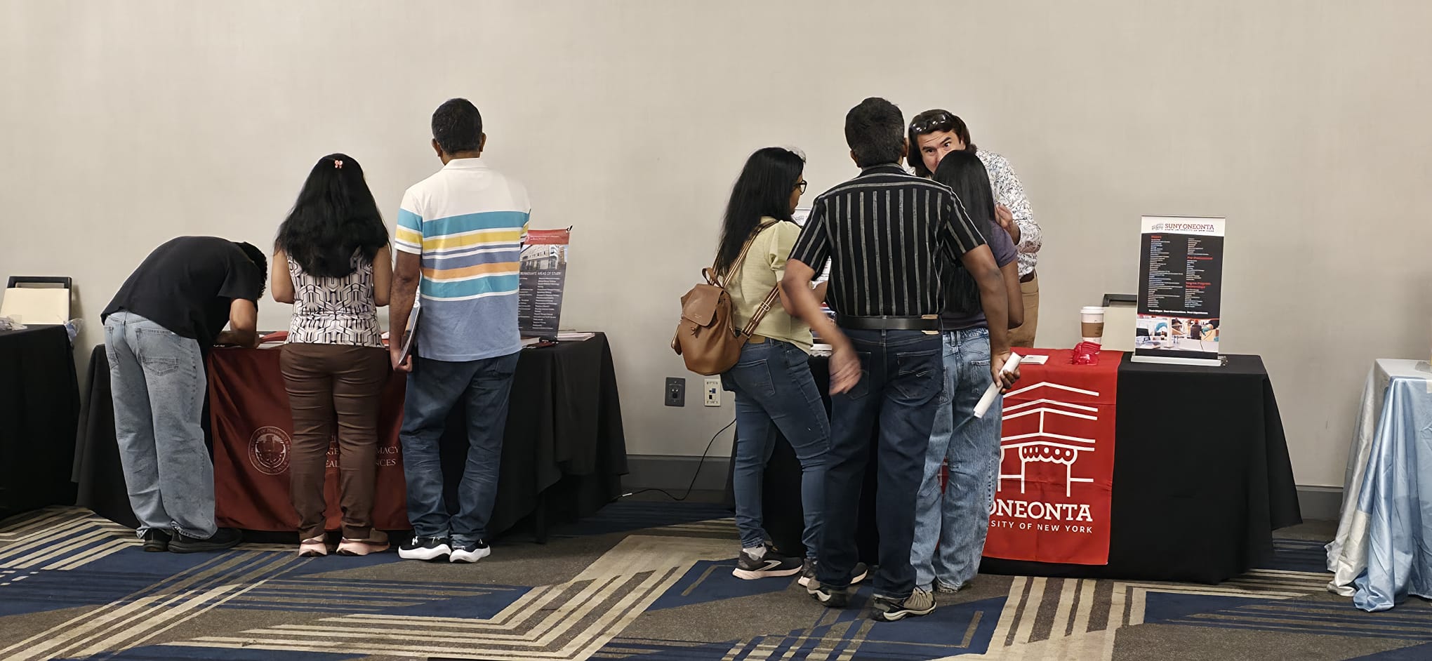 Families at the SUNY Oneonta and Massachusetts College of Pharmacy and Health Sciences tables discussing healthcare pathways
